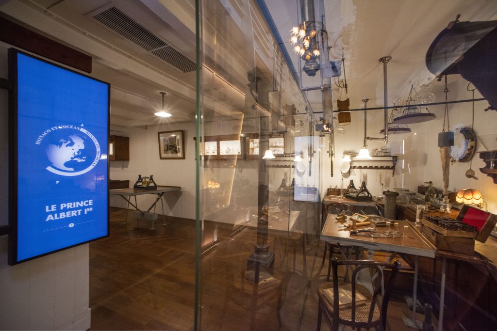« Monaco et l’Océan : de l’exploration à la protection ».
Espace dédié à l’engagement de la Principauté et de ses Princes en faveur des Océans.
UNE EXPÉRIENCE DE VISITE PORTÉE PAR UNE SCÉNOGRAPHIE IMMERSIVE
Le Musée océanographique , lieu chargé d’histoire au patrimoine riche, dévoile un nouvel espace sans précédent. « Monaco et l’Océan » propose un véritable voyage dans le temps, de 1906 à nos jours. Confiée à l’agence Koya Farell, la scénographie se veut immersive, digitale, engageante.
Ici, les nouvelles technologies sont mises au profit de l’histoire, des collections patrimoniales et scientifiques de l’établissement centenaire permettant le mariage singulier du réel et du virtuel, l’alliance parfaite de l’objet et du numérique. Le parcours est composé de surprises et d’étonnements, pour stimuler la réflexion, mobiliser les sens, capter l’attention du public qui devient acteur de sa visite, puis acteur pour les océans.
« Monaco & l’Océan » a la volonté de partager de manière ludique des décennies de recherches, de découvertes et de savoir. Le parcours visiteur s’appuie sur un itinéraire interactif où l’Homme regarde d’abord la mer depuis la surface, puis, il plonge dans les profondeurs pour s’élever à nouveau au-dessus de l’immensité de l’océan, afin d’observer et mieux comprendre les grands enjeux de la planète bleue, et de sa conservation.
Exploratoire et intimiste, le parcours retrace progressivement l’histoire et l’actualité d’une relation particulière : celle de 3 hommes, 3 destins, entre passé, présent et un futur qu’il reste à construire.